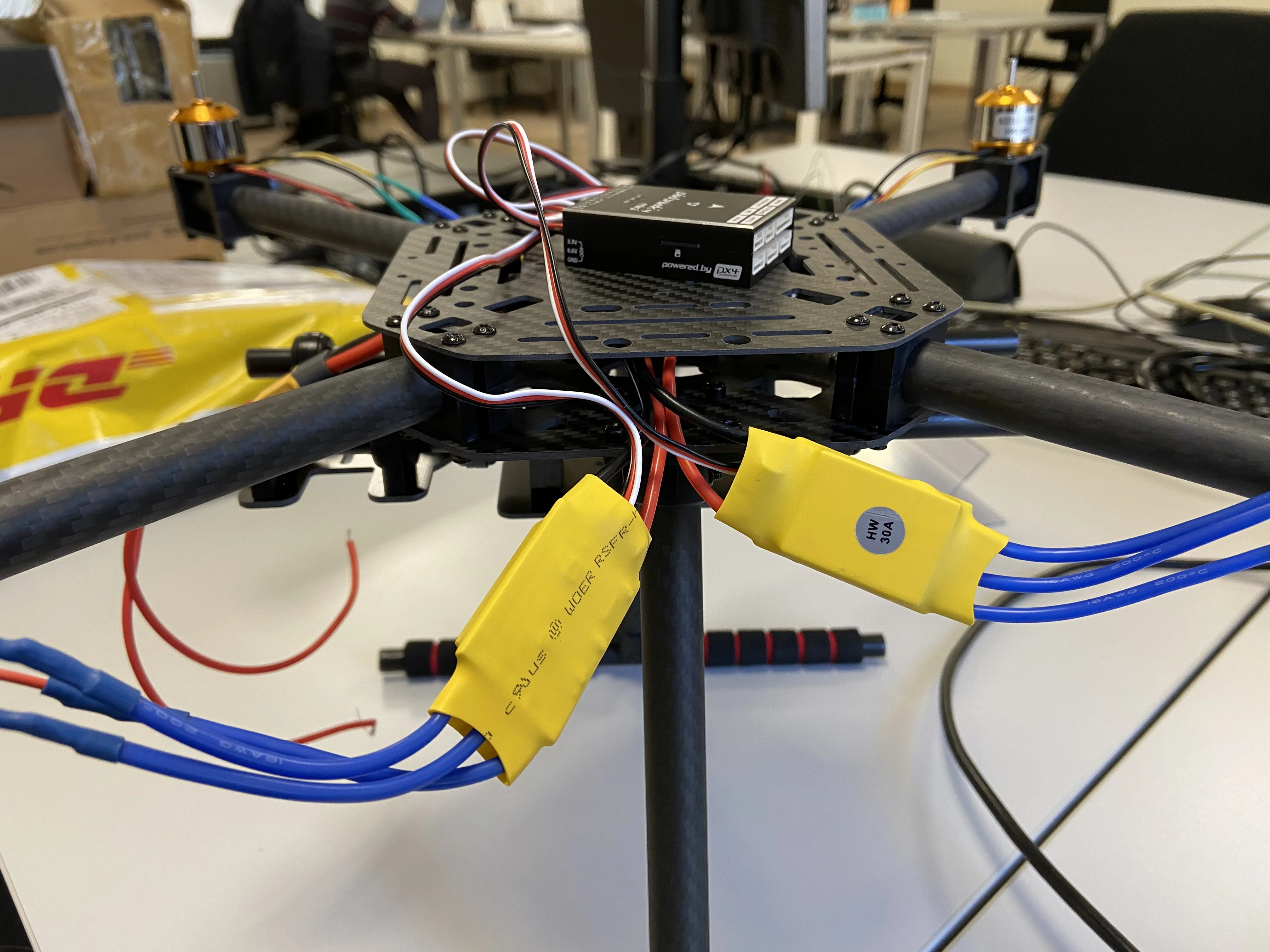 Holybro X500 electronics stack open — Pixhawk 4 Mini autopilot (black box) and Raspberry Pi companion computer mounted in their 3D-printed holders between the two carbon-fibre plates. Custom power distribution PCB and wiring harness also visible.