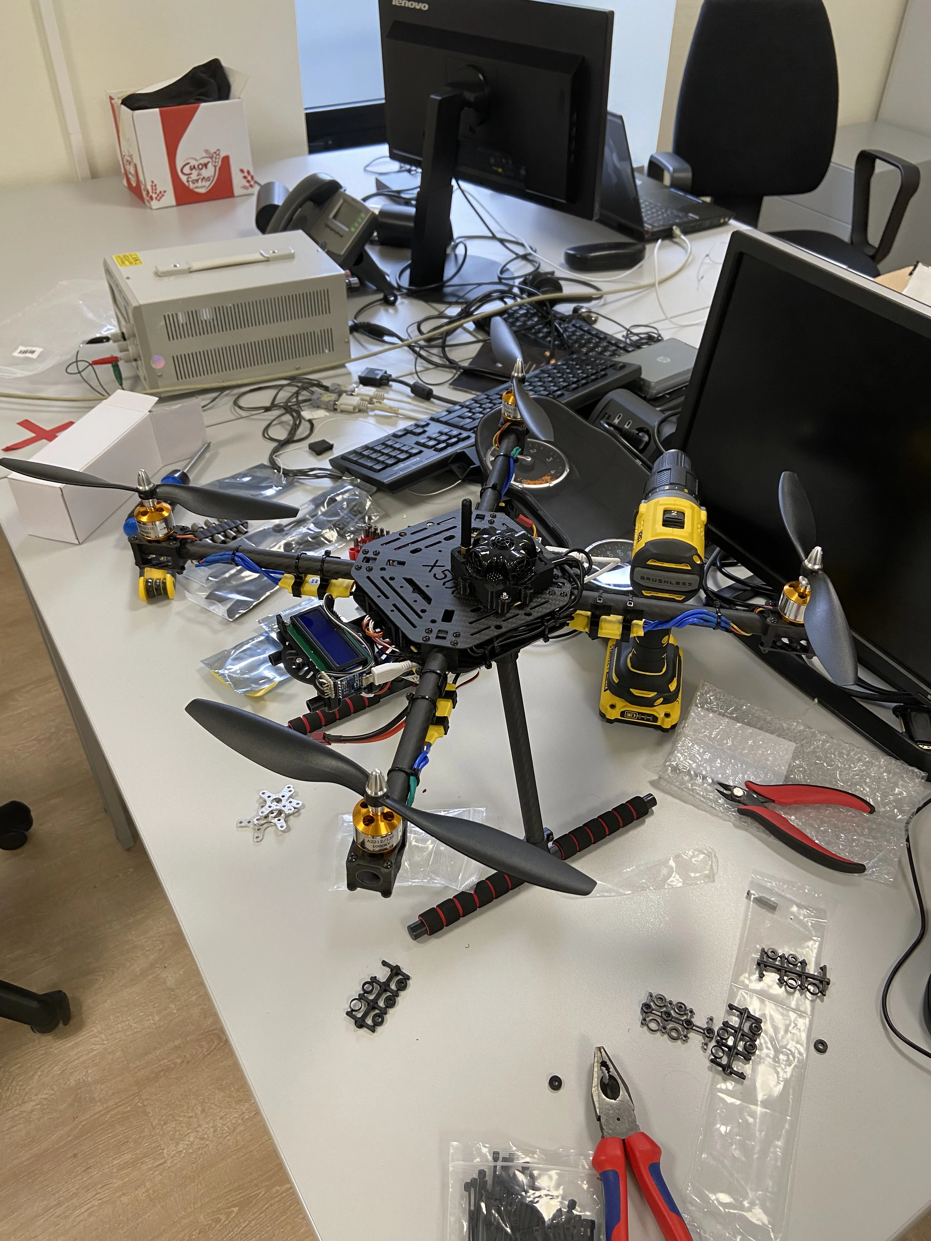 Holybro X500 quadrotor — fully assembled platform with all electronics enclosed between the two carbon-fibre plates. Marvelmind ultrasonic beacon (HW v4.9-NIA) mounted on the frame for indoor GPS-denied positioning. Yellow Kotleta20 ESCs visible on the arms.